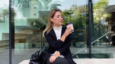 Modern bir halk şehrinde sıradan bir kahve molası: güzel ve rahat sarışın Latin yönetici halka açık bir meydanda kahve yudumluyor