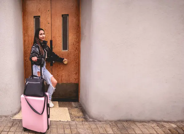 Stylish travel and urban exploration: vibrant young latina brunette with fashion look and pink suitcase exploring city historic district and downtown