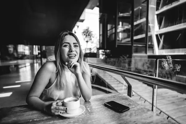 Casual business meeting in a outdoor city coffee: beautiful blonde latina executive sipping coffee and chatting in a scenic city spot (in black and white)