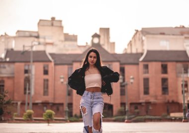 Şık seyahat ve şehir keşfi: Eski tarihi bölgedeki terk edilmiş binaların önünde şık görünümlü canlı Latin esmer