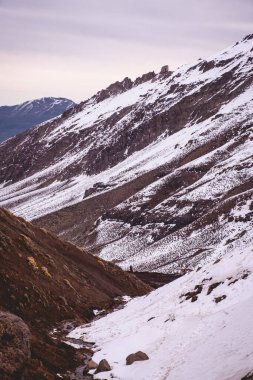 Beyaz kış dağları: soğuk bir günde karla kaplı dağların büyüleyici manzarası ve bulutlu gökyüzü