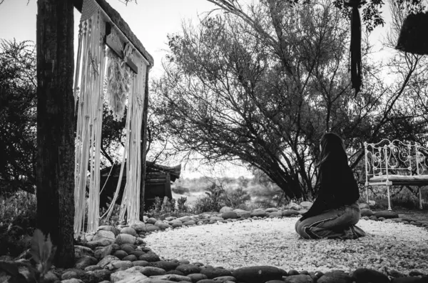 Spiritual healing in nature: woman finds tranquility on her knees on a quartz bed nestled in mountainous mystique (in black and white)