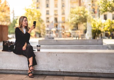 Halka açık bir yerde kahve molası: Güzel ve gevşemiş, kahve fincanı kullanan Latin bir yönetici.