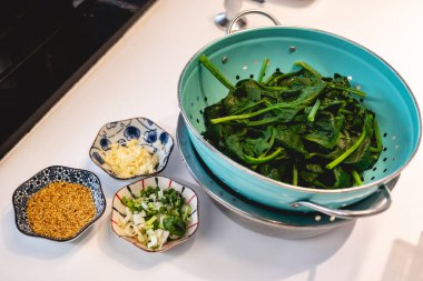 Beyaz mutfak tezgahında Koreli ıspanak tabağı Sigeumchi Namul 'un malzemeleri.