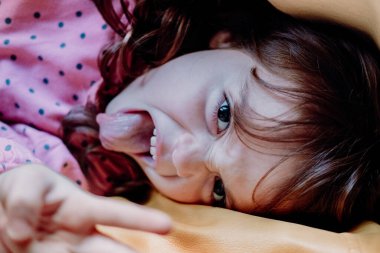 Cute but disobedient five-year-old red-haired girl misbehaving and causing trouble at home. Perfect for parenting, discipline, and problem child themes. She wear pink red dot dress.