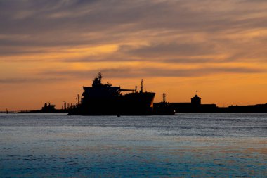 Gün batımında nakliye gemilerinin siluetleri.