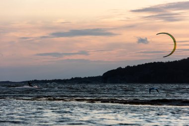 Göteborg, İsveç - 10 Ekim 2021: Uçurtma sörfçüleri gün batımında sahilde uçurtma uçuruyorlar .