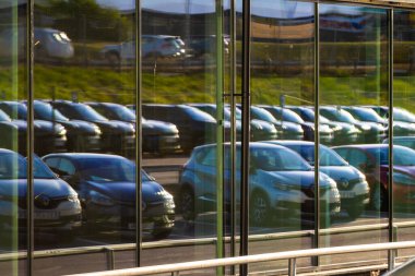 Göteborg, İsveç - 30 Temmuz 2022: Bir araba galerisinde cam cephede yansıtılan uzun sıra arabalar.