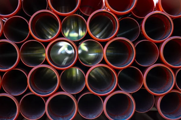 Büyük turuncu plastik PVC borular yığını.