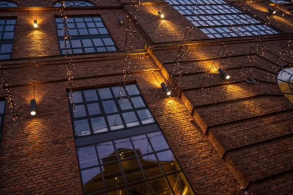 Christmas decoration lights hanging from  the facade of a brick building.
