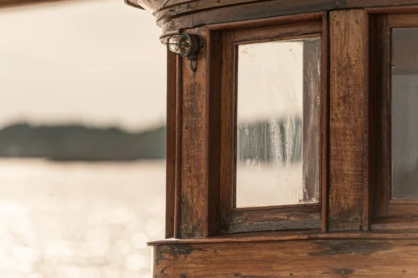 Windows of a wheelhouse of a wooden boat.