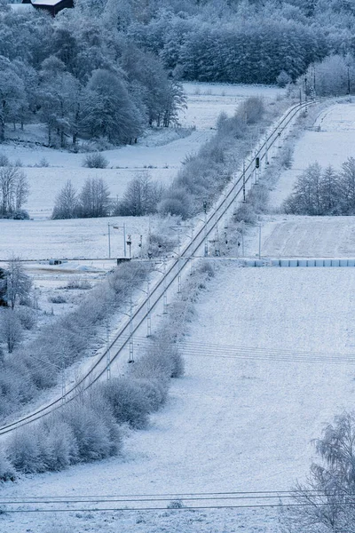 Railway line crossing fileds in a cold snowy winter.