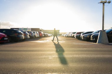 Out of focus image of a person walking across a parking lot.