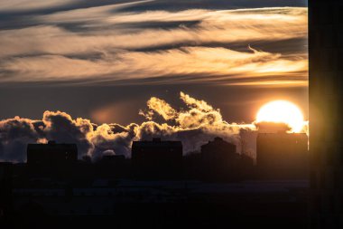 Sun setting behind apartment buildings.
