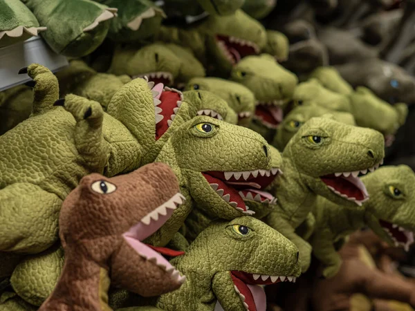 Long row of soft toy dinosaurs in a shop.