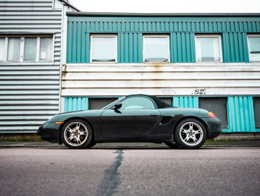 Gothenburg, Sweden - november 28 2022: Black 2000 Porsche Boxter convertible by an industrial building.