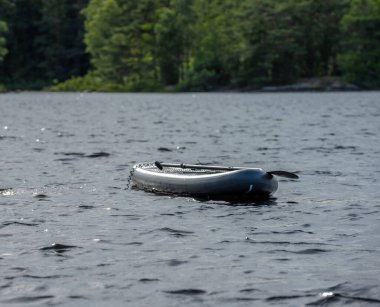 Grey SUP board floating in a lake.
