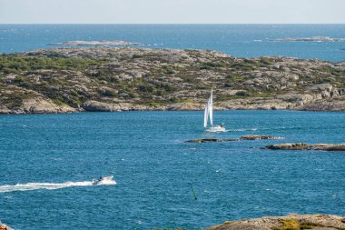Kungalv, Sweden - July 15 2022: Motorboat and sailboat passing through a sound.