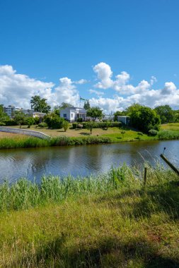 Landskrona, İsveç - 10 Temmuz 2022: Hendeğin yanındaki beyaz ev ve bahçe.