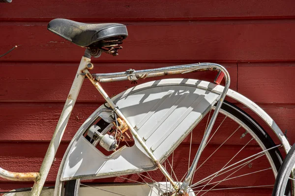 旧的生锈的白色自行车靠在红墙上 — 图库照片