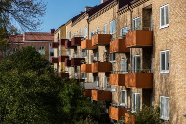 Göteborg, İsveç - 15 Mayıs 2020: Tuğladan bir apartmanın güney yüzünde balkonlar.