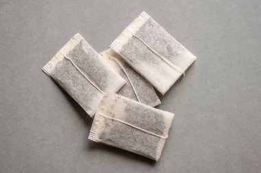 Gri masada dört kullanılmamış çay poşeti..