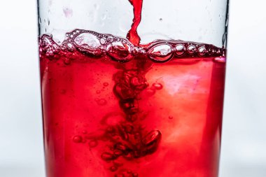 Kırmızı sıvı bardağa dökülüyor. Beyaz arkaplan..