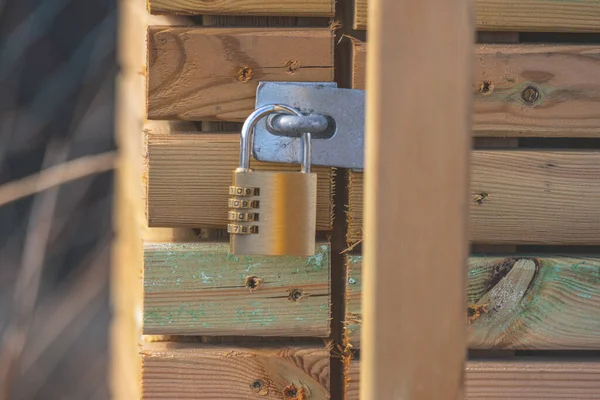 Combination padlock on a wooden shed.