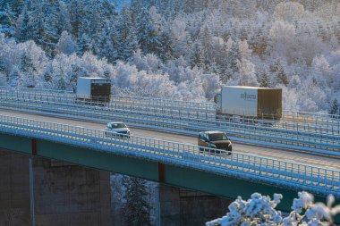 Stenungsund, İsveç - 3 Ocak 2023: Kışın otoyol köprüsünden geçen arabalar ve kamyonlar.