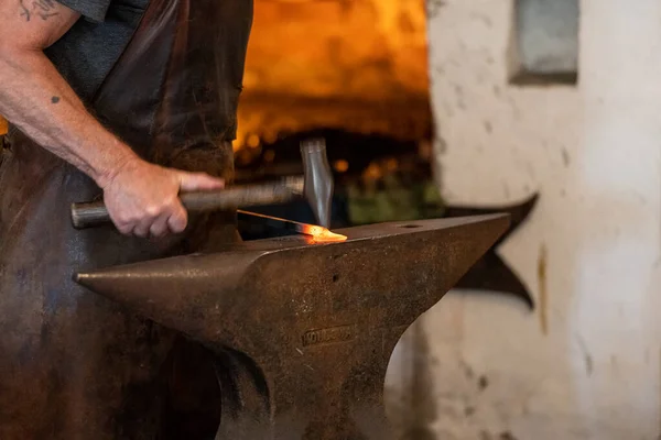 Herrero trabaja en un yunque. producto de forja maestra. herramientas y  yunque de herrero. herrero trabajando al aire libre.