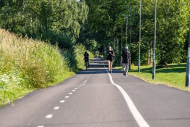 Göteborg, İsveç - 27 Temmuz 2022: İnsanlar bisiklete biniyor, koşuyor ve bir kütük ve düz yol boyunca yürüyor.