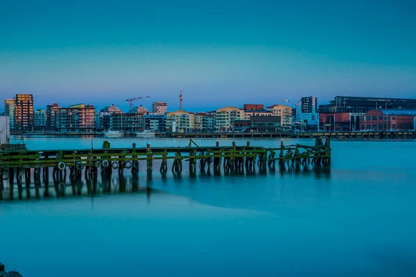 stock image Gothenburg, Sweden - March 29 2014: Old wooden pier opposite new apartment housing by the river.