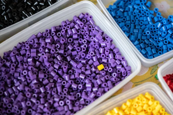 stock image Purple beads in a box with one yellow bead.