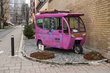 Göteborg, İsveç - 25 Şubat 2023: Pembe tuktuk bir binanın yanına park edildi.