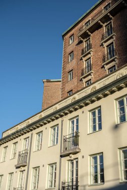 Gothenburg, İsveç - 05 Mart 2023: Başka bir beyaz binanın tepesindeki tuğla apartman.