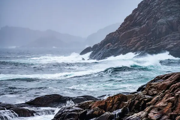 stock image Waves crashing against cliffs during a winter storm.