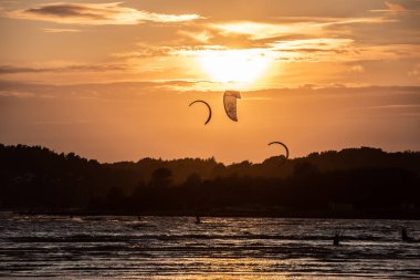 Göteborg, İsveç - 10 Ekim 2021: Kiteboardcular gün batımında plajda uçurtma sörfü yapıyorlar.