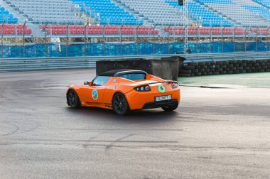 Gothenburg, İsveç - 28 Eylül 2012: Turuncu Tesla Roadster bir yarış pistinde çok hızlı sürüyor.