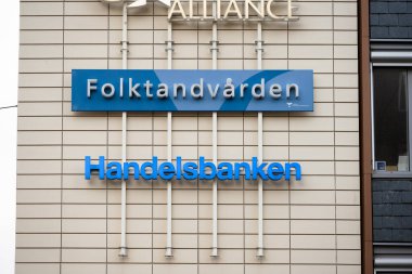 Göteborg, İsveç - Nisan 06 2023: Folktandvarden ve Handelsbanken bir ofis duvarında tabelalar.