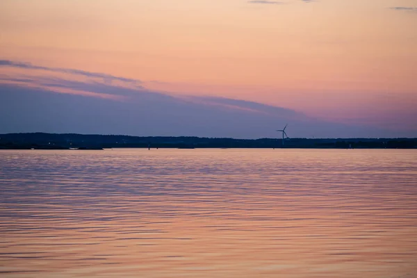 Evening light over a wind turbine by the sea.