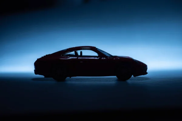 青い背景にモデルのおもちゃのスポーツカーのシルエット ストック写真