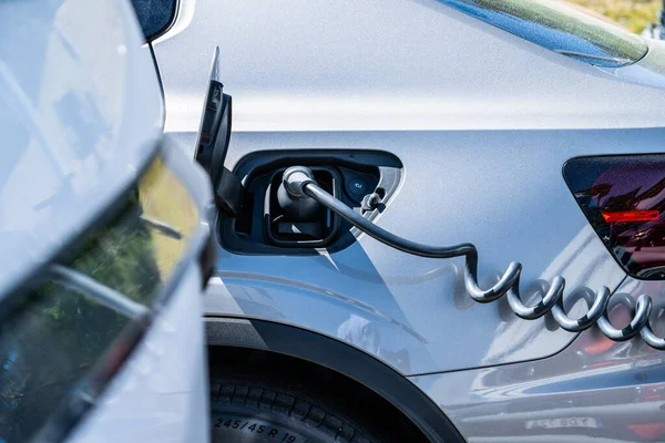 Göteborg, İsveç - 31 Mayıs 2023: Otoparkta gümüş elektrikli araba şarj ediliyor.