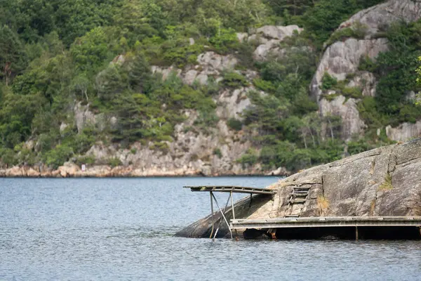 Old wooden diving board on a cliff by a fjord.