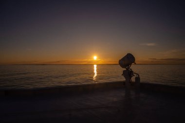 Gün batımında büyük bir geminin arama ışığı.