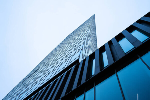Looking up a tall scyscraper glass facade.