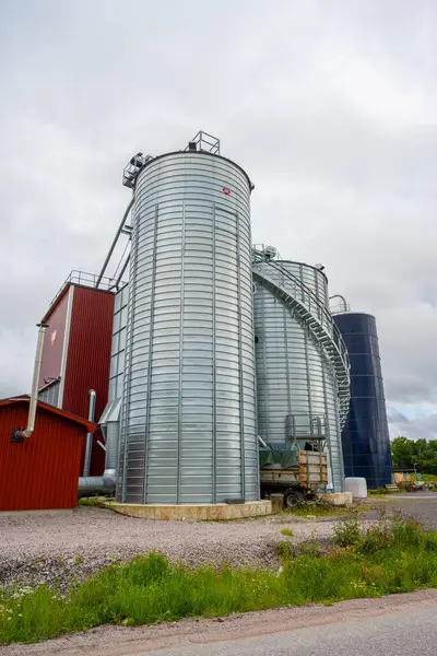 Large shiny metal grain silos at a farm.