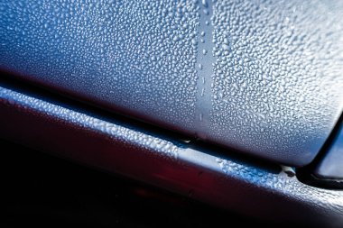 Gümüş bir arabanın kaputunda damlacıklar var..