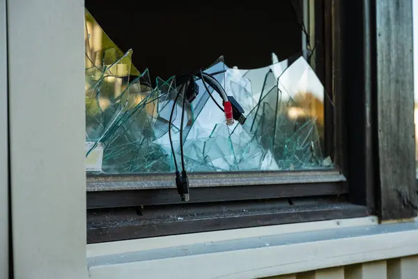 Computer cables hanging out of a broken window after a break in and theft.
