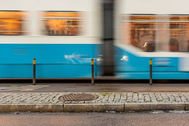 Göteborg, İsveç - 10 Ocak 2021: Mavi ve beyaz bir tramvayın geçişinin uzun pozlu fotoğrafı.