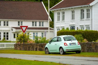 Lindesnes, Norveç - 07 Ağustos 2022: Nane yeşili Fiat 500 arabası geleneksel beyaz ahşap evler.
